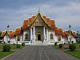 Bangkok 02 02 Wat Benchamabophit Marble Wat Long View Wat Benchamabophit, called the Marble Wat because of the white Carrara marble of which it's constructed, is an early-20C temple designed by Prince Narai, the half brother of Rama V. It's the most modern and one of the most beautiful of Bangkok's royal wats. Unlike the older complexes, there's no truly monumental wihaan or chedi dominating the grounds. Many smaller buildings reflect a melding of European materials and designs with traditional Thai religious architecture. Even the courtyards are paved with polished white marble.